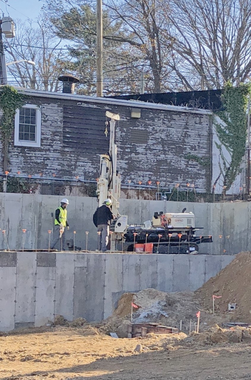 Hotel construction site manager builds soil ramp to allow 7822DT access behind retaining wall in order to conduct DT 325 SPT OTE geotechnical sampling.