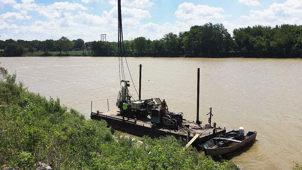 Because of the steep banks on both sides of the river, Mannik & Smith Group lowered their 7822DT onto a barge with a crane, and performed 20-ft. deep rock cores at each of the seven proposed foundation locations.