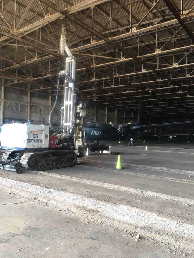 The Stearns Drilling 8140LS Rotary Sonic sets up inside one of the production buildings at the former Willow Run Powertrain Plant in southeastern Michigan for soil sampling and monitoring well installation. In the background sits a DeHaviland DHC-4 Caribou.