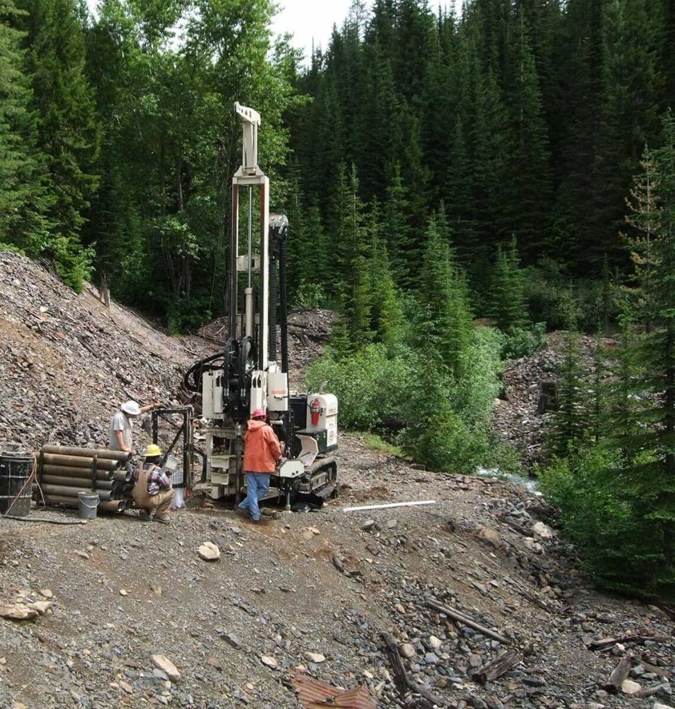A Geoprobe® Rotary Sonic rig and field team work at a remote mine rock dump site in the northern United States. One of the borings went to 55 meters within the Troutdale Formation, an alluvial sand and gravel deposit, characterized by cemented gravels, cobbles and ‘Volkswagon’ sized boulders. The field team attributes the success of the project to the power of the Geoprobe® Sonic Head. Even with soft ground conditions, rain showers, and other environmental concerns, the tracked rig allowed the field team to