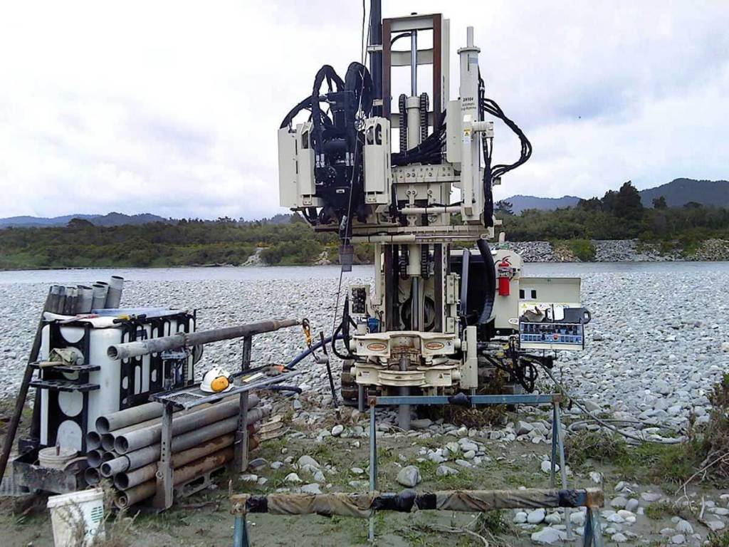 Working in New Zealand, this Geoprobe® Rotary Sonic was used with sonic dual tube tooling to retrieve samples of mostly cobble-sized Greywacke on the west coast of the south island. The filled liners contained vesicular Basalt rock. Because the control panel on the Geoprobe® Sonic Rig is adjustable, it can be located at a comfortable distance from the working hole to keep the rig operator safe and away from spinning tooling.