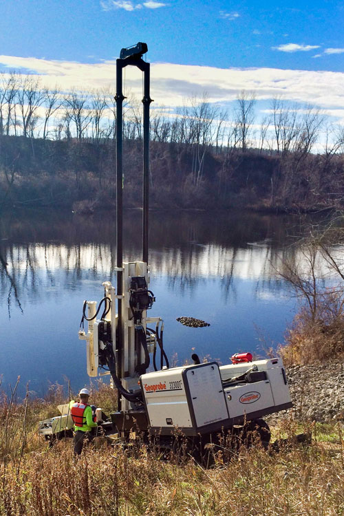 Winch mast oscillation makes easy work of steep banks of an earthen dam for split spoon, Macro Core® soil sampling, and wireline rock coring.
