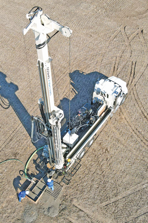 Dual pivot jib on rig capable of air drilling or use as a mud drill enables accessing both sides of rig.